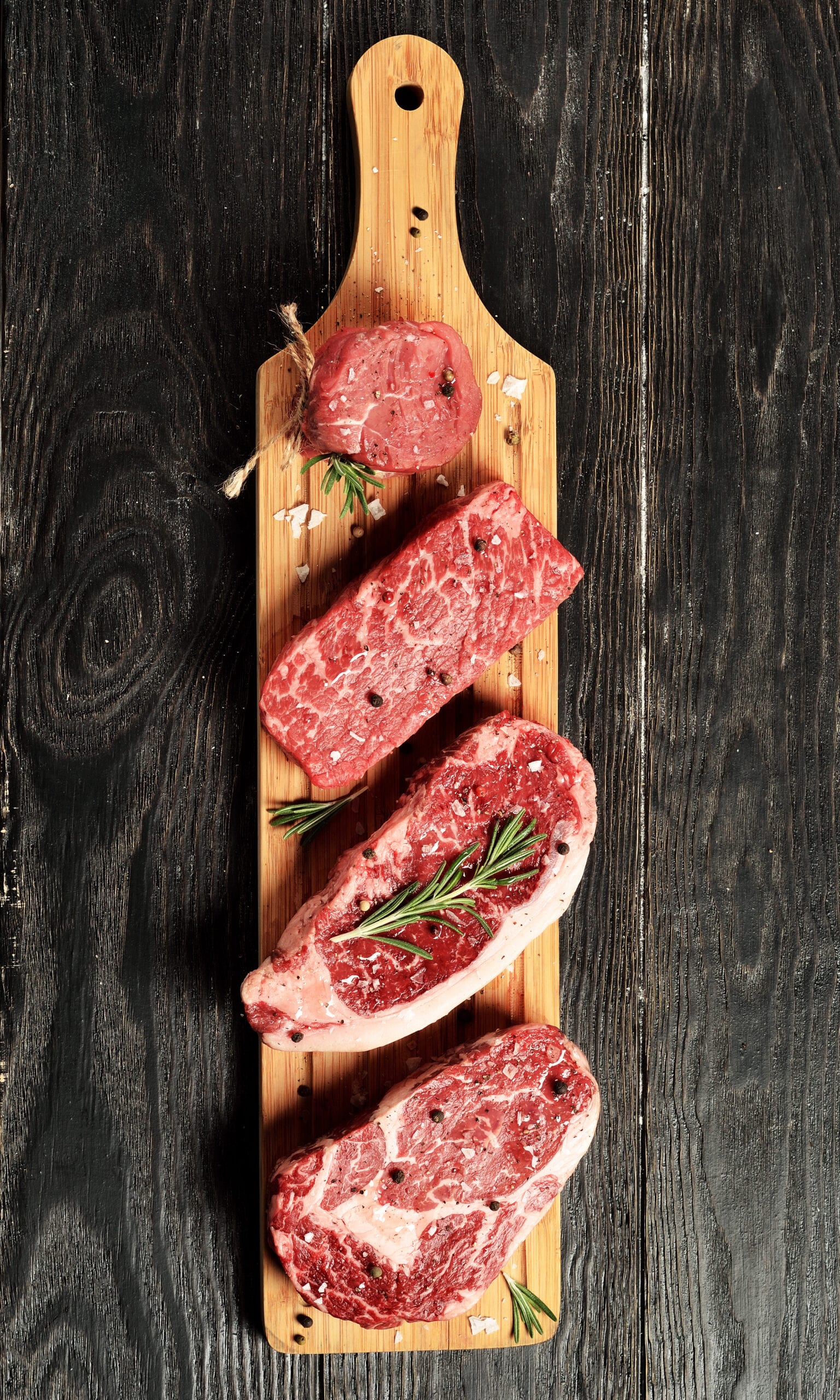 Fresh raw Prime Black Angus beef steaks on wooden board